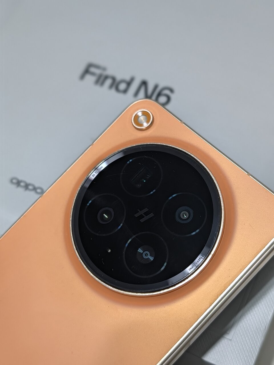 Primo piano del modulo fotocamere circolare dell'OPPO Find N6 con le ottiche e il logo Hasselblad, sopra la confezione