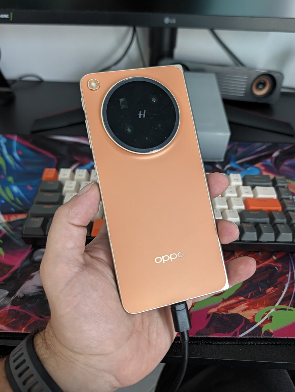 OPPO Find N6 chiuso tenuto in mano, retro arancione con modulo fotocamere circolare e logo OPPO