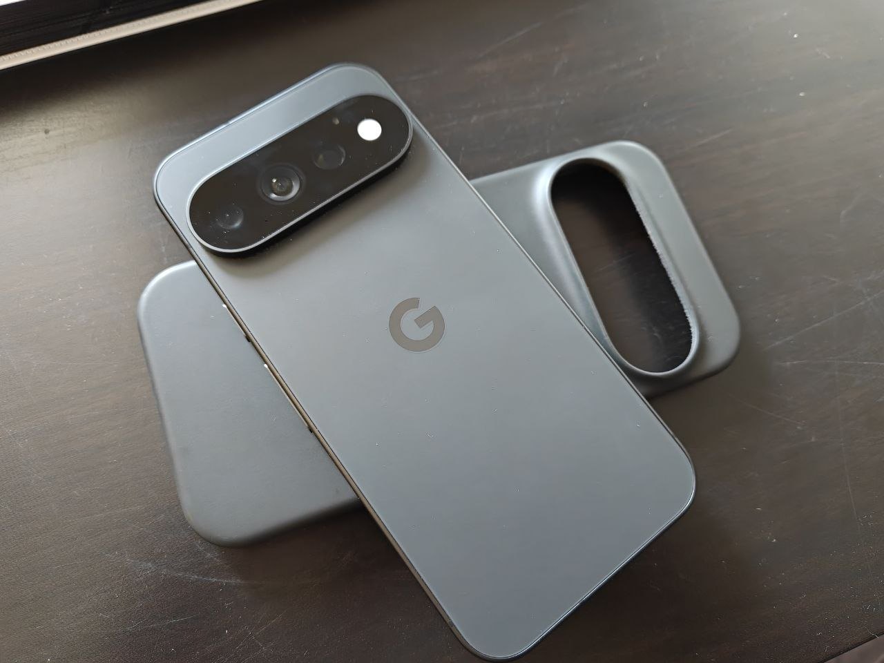 Google Pixel 11 Pro appoggiato di schiena sulla scrivania, con la barra delle fotocamere e il logo G